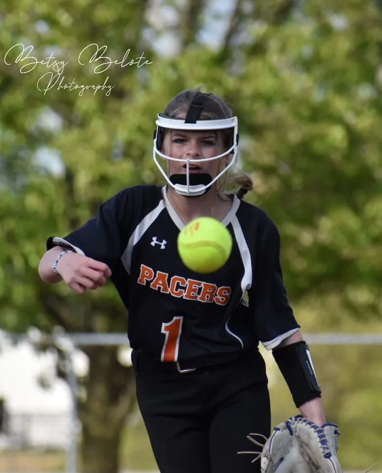 Female softball player fielding ball mid-air during game