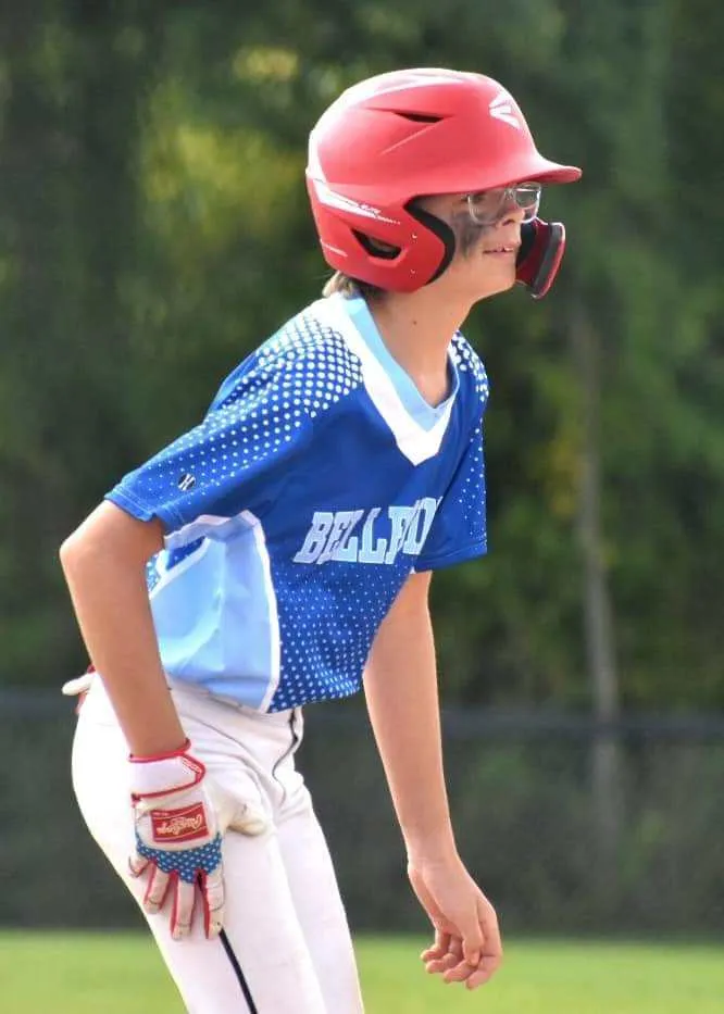 Young male baseball player standing on base in blue jersey